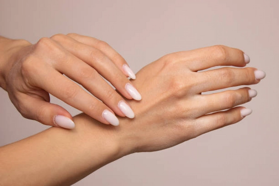 Hands receiving moisturizing treatment for dry skin.